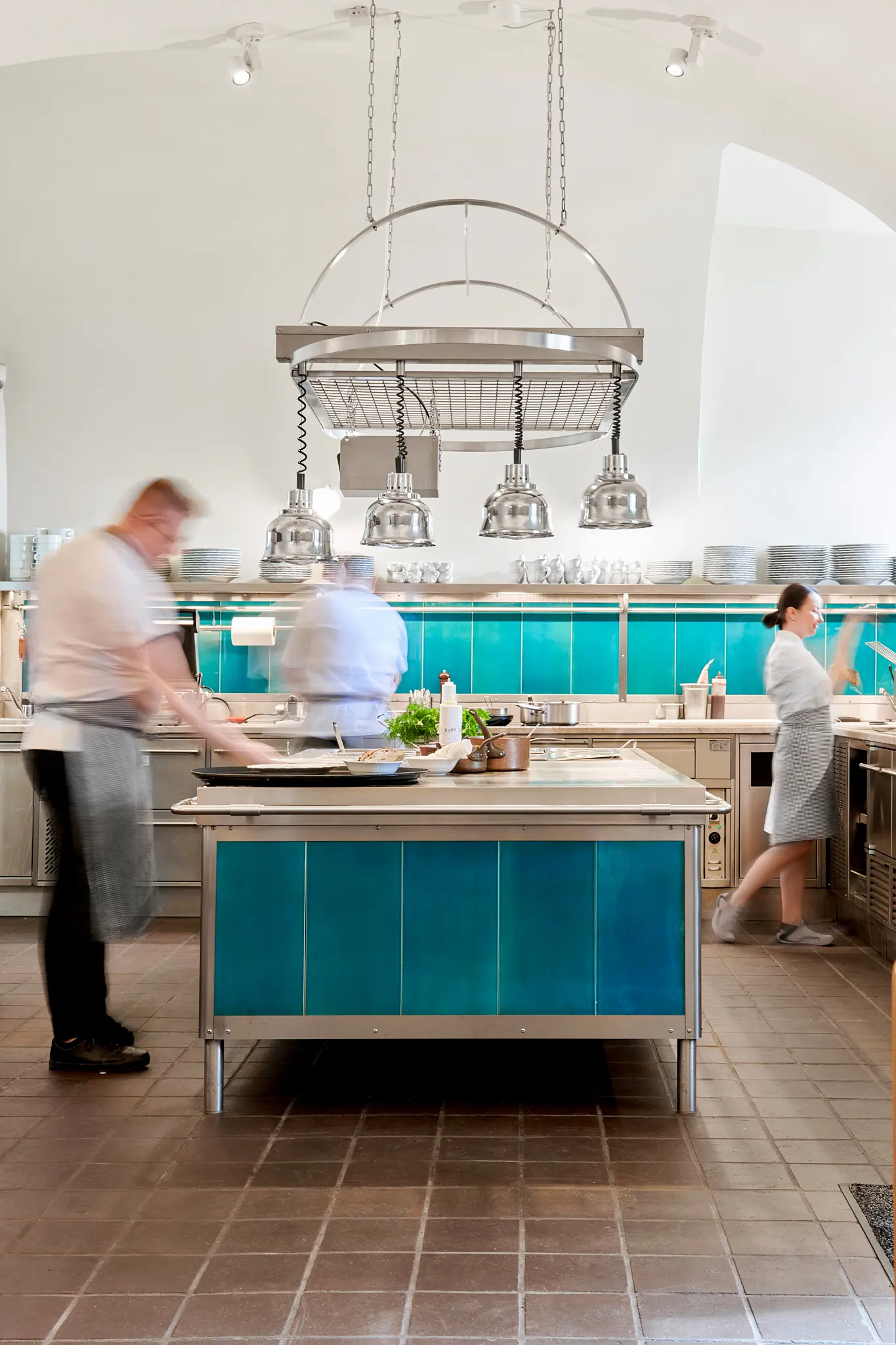 Open restaurant kitchen with chefs at work around a central prep station.