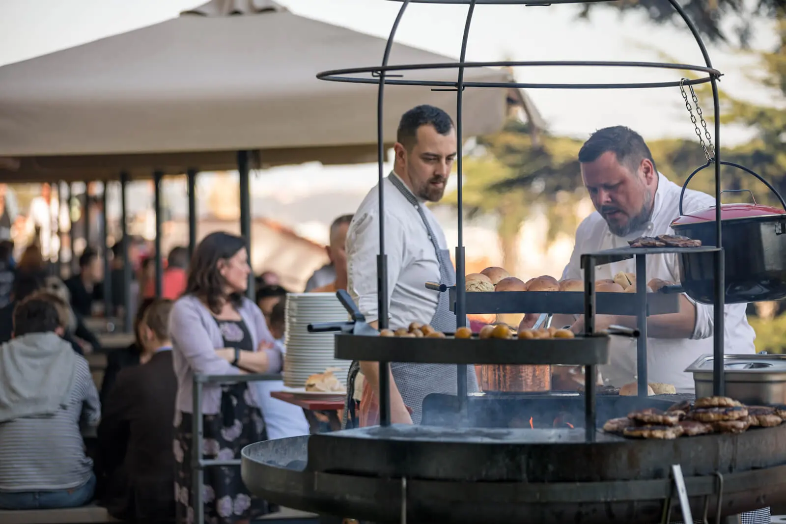 Chefs preparing food on an outdoor grill.